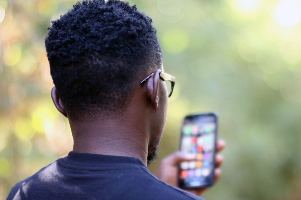 A young man in Kenya checks his mobile phone outdoors.